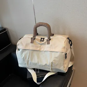 Side view of beige travel duffel bag with textured front panel and brown handles