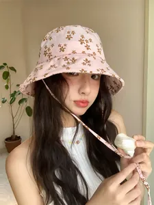 Gros plan du chapeau bob rose à fleurs sur modèle avec motif marguerite et jugulaire