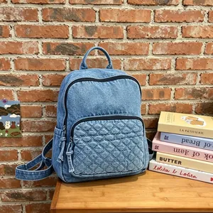 Moderner hellblauer Denim-Rucksack mit Stepptasche vor einer gemütlichen Ziegelwand