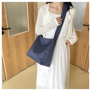 Detail view of navy checkered nylon crossbody bag worn by a model in casual setting