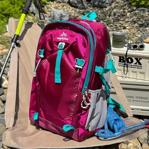 Fuchsia hiking backpack with teal accents, waterproof fabric, shown in outdoor camping setting