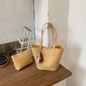 Hand-woven beige bucket bag with matching pouch shown in a stylish kitchen setting.