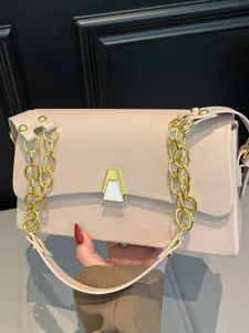 Elegant beige square handbag featuring a gold chain strap and geometric metallic clasp