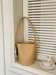 Minimalistische beige geflochtene Beuteltasche mit Perlenquaste und Gurt