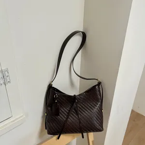 Λεπτομερής λήψη της σκούρας καφέ πλεγμένης δερμάτινης υφής αυτής της τσάντας tote