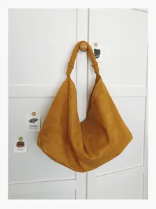 Close-up of retro mustard yellow suede hobo bag with knotted handle detail