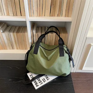 Dettaglio di una grande borsa da viaggio a scacchi verdi davanti a una libreria bianca