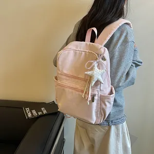 Vista detallada de una mochila rosa para mujer con un lindo colgante de estrella incluido