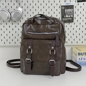 Detail of a vintage brown faux leather commute backpack with buckle straps on a desk.