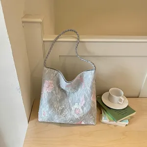Close-up detail of exquisite flower embroidery on a light blue lace shoulder bag