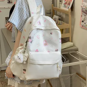 Detailed view of the cute white backpack with cartoon patterns and plush charm