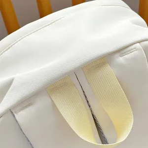 Close-up of durable cream backpack handle with reinforced stitching and textured fabric