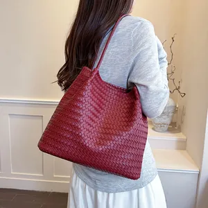 Detailed shot of a red woven tote bag with vintage Intrecciato style carried by model.
