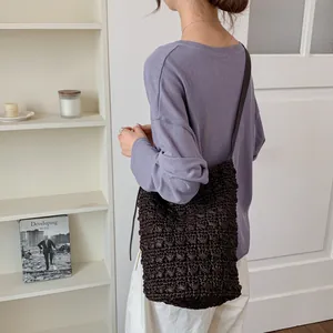 Detailansicht einer braunen Strohtasche im Bucket-Stil kombiniert mit lila Outfit