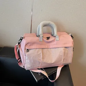 Close-up detail of a pink travel duffle bag featuring a triangular grid pattern and grey handles