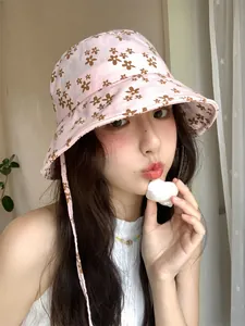 Vue détaillée d'un chapeau bob rose à fleurs porté par un mannequin asiatique au soleil