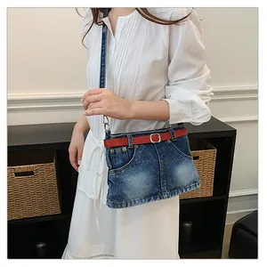 Detail of fashion denim crossbody bag featuring a unique mini-skirt design with red belt