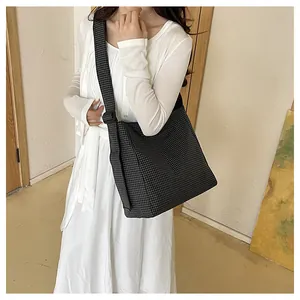 Detailed view of the large capacity nylon grid crossbody bag worn by a female model