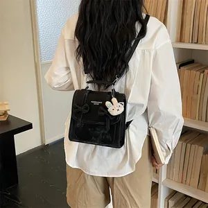 Vista posteriore dello zaino nero stile college con fiocchi indossato da modella in libreria