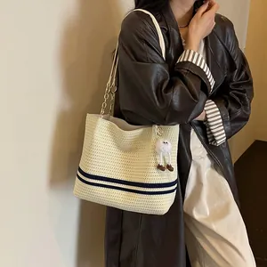 Close-up detail of a stylish striped woven tote bag styled with a dark leather trench coat