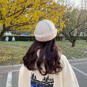 Back view of a woman wearing a warm beige plush-trimmed Miki hat during the autumn season.