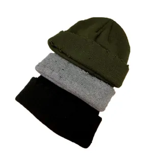 Lot de trois bonnets en maille vieillis empilés en vert olive, gris et noir.