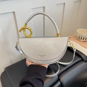 Moderne silberne Satteltasche für Damen mit einzigartigem goldenen Spiralknoten-Handgriff.