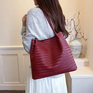 Detailed view of a red woven leather tote bag worn by a model as a shoulder bag