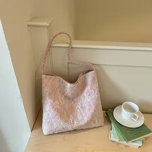 Pink flower embroidered hobo shoulder bag with elegant twisted rope strap in a lifestyle setting