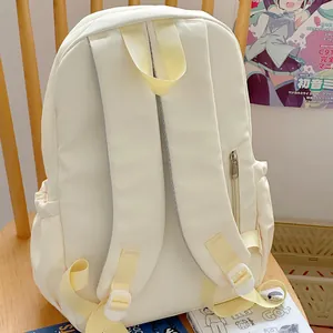 Detailed back view of a minimalist white women's fashion backpack on a wooden chair