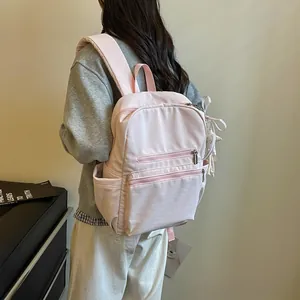 Vista trasera de una elegante mochila rosa ligera llevada por una modelo de perfil