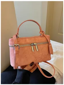 Macro view of salmon pink textured box handbag featuring elegant silver zipper and hardware