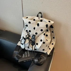 Close-up detail of casual polka dot canvas backpack on a black leather surface