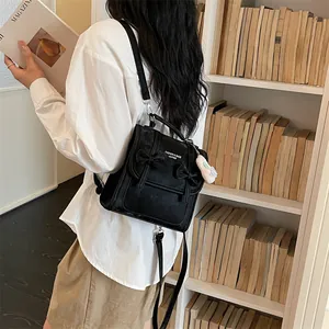Elegante zaino nero in stile college mostrato su modella in una biblioteca