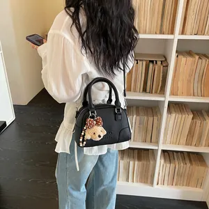Detailed view of black Boston handbag with plush bear keychain in lifestyle setting