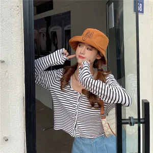 A young woman wearing a stylish orange bucket hat with cute bunny ear embroidery detail