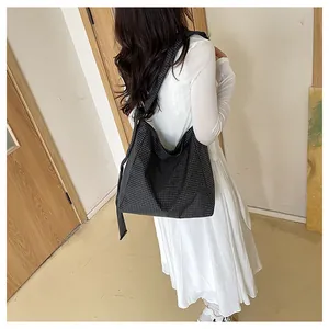 Stylish large capacity black and white plaid shoulder bag shown worn by a model in a white dress