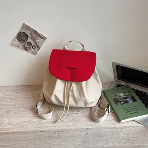 Gros plan sur le rabat rouge contrasté d'un sac à dos en toile crème sur un bureau