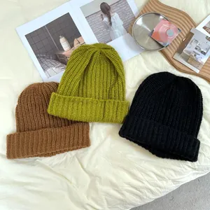 Lifestyle flat lay of three oversized chunky knit beanies in brown, lime green and black.