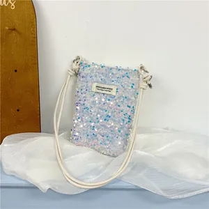 Dettaglio di una borsa a tracolla bianca con paillettes iridescenti e spalline sottili.