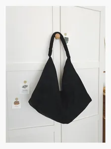 Minimalist large black suede tote bag hanging on a white cabinet door detail view