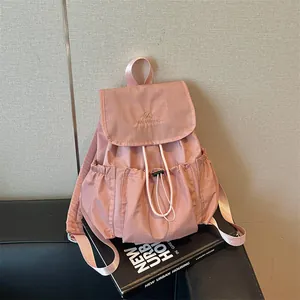 Elegant pink pleated drawstring backpack with embroidery logo displayed on a magazine