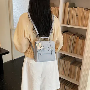 Dettaglio di un mini zaino azzurro in stile preppy con fiocchi indossato da una donna