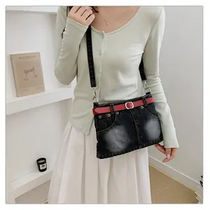 Detailed view of creative denim crossbody bag styled like mini jeans with red belt
