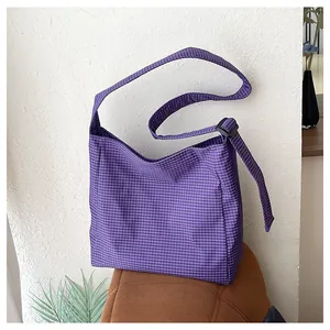Detailed view of casual purple checkered nylon crossbody bag placed on a textured chair