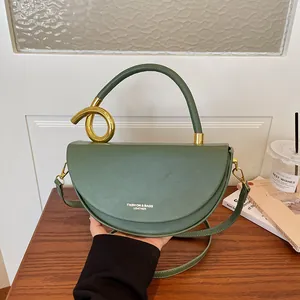 Detailansicht einer grünen Satteltasche mit einem einzigartigen goldenen Knotengriff.