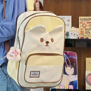 Close-up of a cute cream cat-face backpack featuring 3D ears and plush keychain.