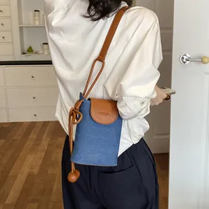 Back view of a woman wearing a minimalist blue denim crossbody phone bag with leather trim