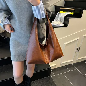 Vista detallada que muestra la textura de cuero brillante del bolso hobo marrón retro.