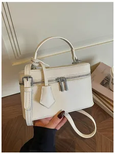 Detailed view of cream-white box handbag with silver hardware and shoulder strap